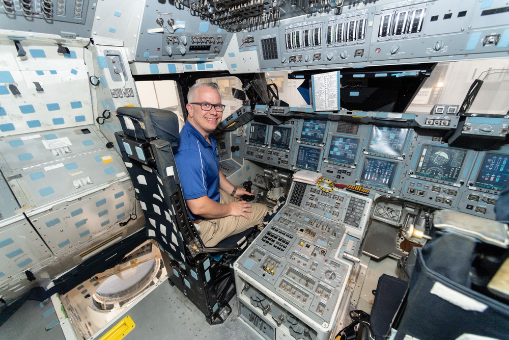Steven Riley in the Shuttle Crew Compartment II mockup inside the Space Vehicle Mockup Facility. 